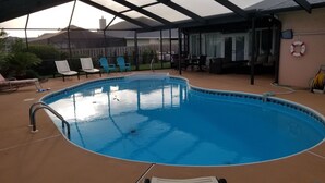 A covered swimming pool with a curved edge, surrounded by lounge chairs and a patio area. - Exclusive 2850 sf Pool Home near Perdido Beaches & NAS, Heated Pool, 2 Masters! (Pensacola)