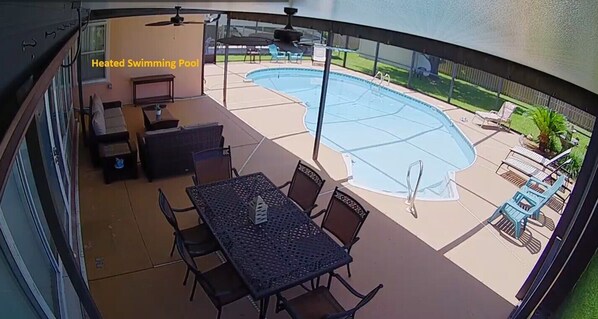 Una piscina climatizada con zona de patio, que incluye una mesa y sillas, y un área de estar cubierta.