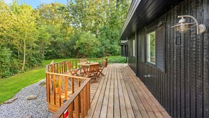 Une terrasse en bois avec des meubles d’extérieur, une petite table et une chaise.