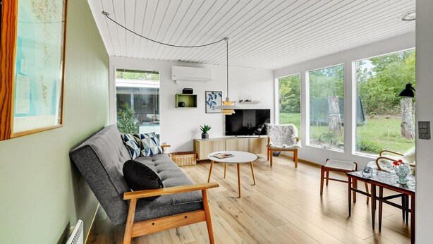 Un salon moderne avec un canapé gris, une table basse en bois et un coin repas comprenant une petite table et des chaises.