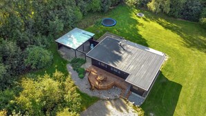 Une maison moderne dotée d’une grande terrasse, d’une piscine et d’une pelouse bien entretenue.