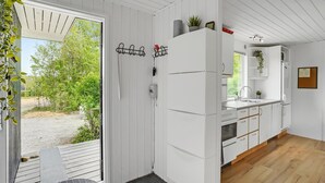 Une cuisine moderne avec des meubles blancs, un four encastré et un évier. Une fenêtre offre une vue sur la verdure à l’extérieur.