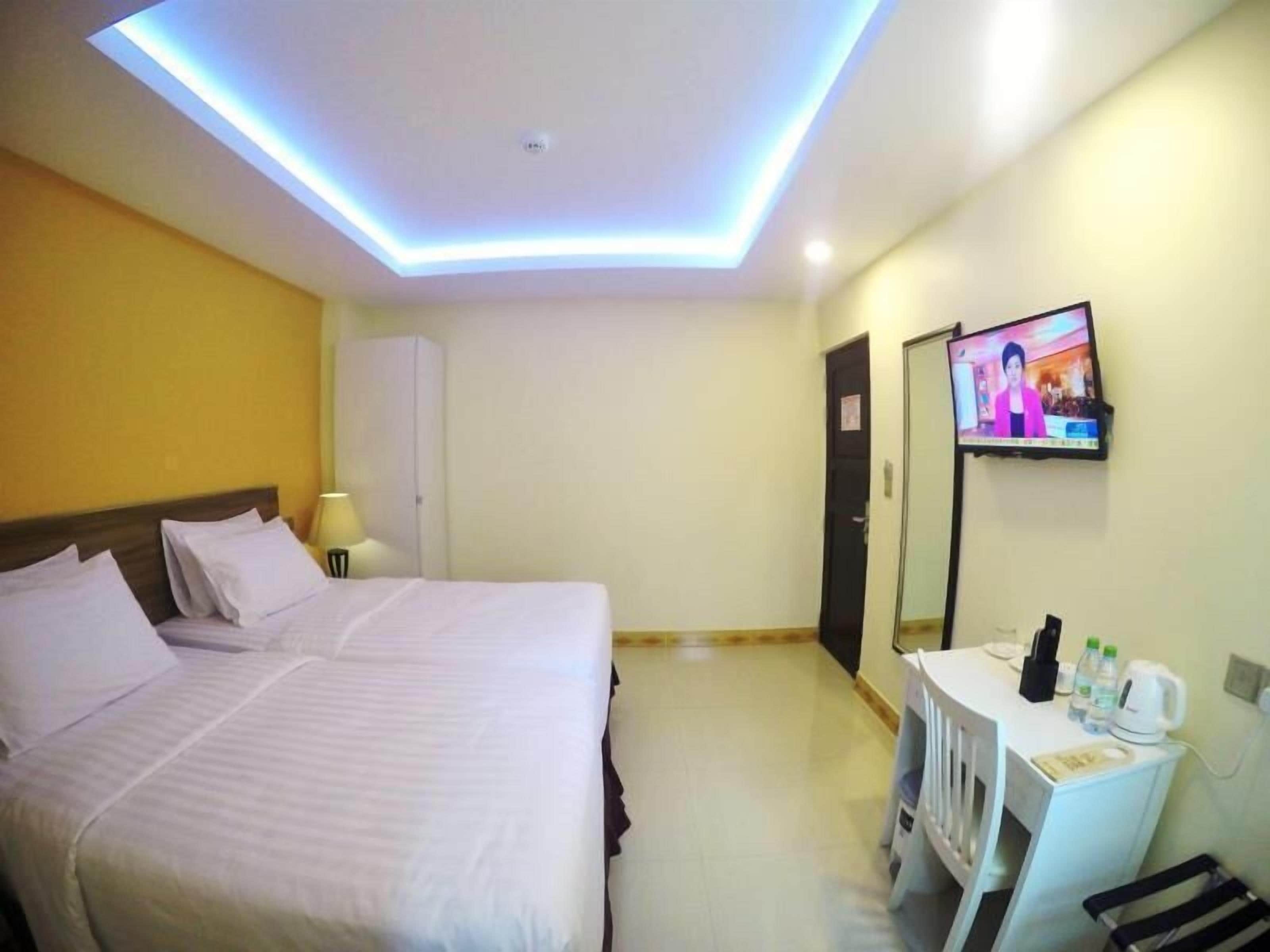 Habitació d'hotel amb dos llits, una taula de nit i un televisor, i un armari.
