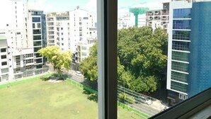 A view of a residential area with multiple high-rise buildings, a green park, and a clear sky. - The Grand View (Malé)
