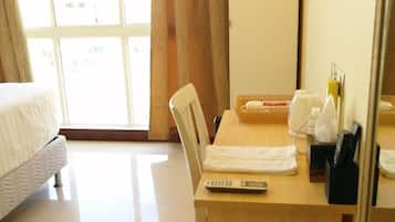 A hotel room with a bed, a desk with a chair, a remote control, and a telephone.