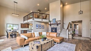 A spacious living room with a leather sectional sofa, a wooden coffee table, and a stone fireplace. - McCall Family Retreat | Pool, Hot Tub & Bikes (McCall)