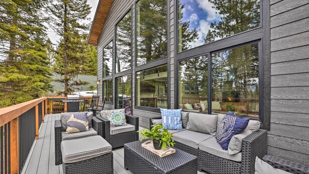 A covered outdoor seating area with wicker furniture and a wooden deck. - McCall Family Retreat | Pool, Hot Tub & Bikes (McCall)