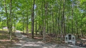 A gravel path leading through a forest with a small cabin and a golf cart. - Quaint Tignall Cabin w/ Deck & Private Dock! (Tignall)