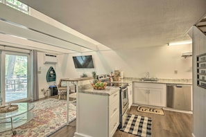 A modern kitchen with a large island, a flat-screen TV, and a dining area with a glass table.