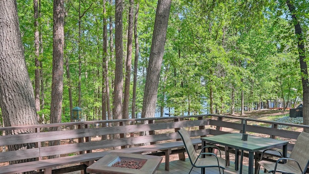 A wooden deck with a stone fire pit, wooden benches, and metal chairs. - Quaint Tignall Cabin w/ Deck & Private Dock! (Tignall)