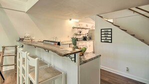 A kitchen with a wooden bar counter, white chairs, a microwave, and a sign instructing to observe social distancing. - Quaint Tignall Cabin w/ Deck & Private Dock! (Tignall)
