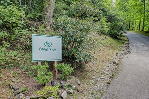 A sign for Stags View with a logo, located beside a road with a forested area.