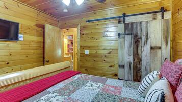Une pièce en bois avec un lit, une télévision et une porte coulissante.