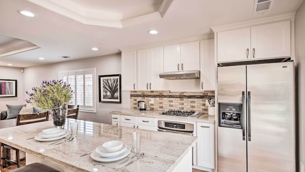 A modern kitchen with white cabinets, stainless steel appliances, and a marble island. - Family Home in Walkable Area Near Silicon Valley! (San Jose)