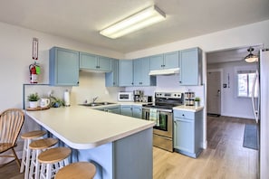 Una cucina con armadietti blu, un'isola centrale con sgabelli, elettrodomestici in acciaio inossidabile e un estintore a parete.