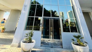 A high-rise building with a modern design, featuring a central entrance with large glass doors and multiple balconies.
