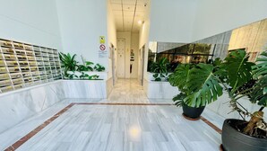 A corridor with marble flooring, potted plants, and a glass wall with a view.