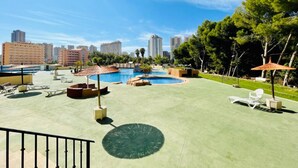 A rooftop pool area with lounge chairs, umbrellas, and a view of the city skyline.