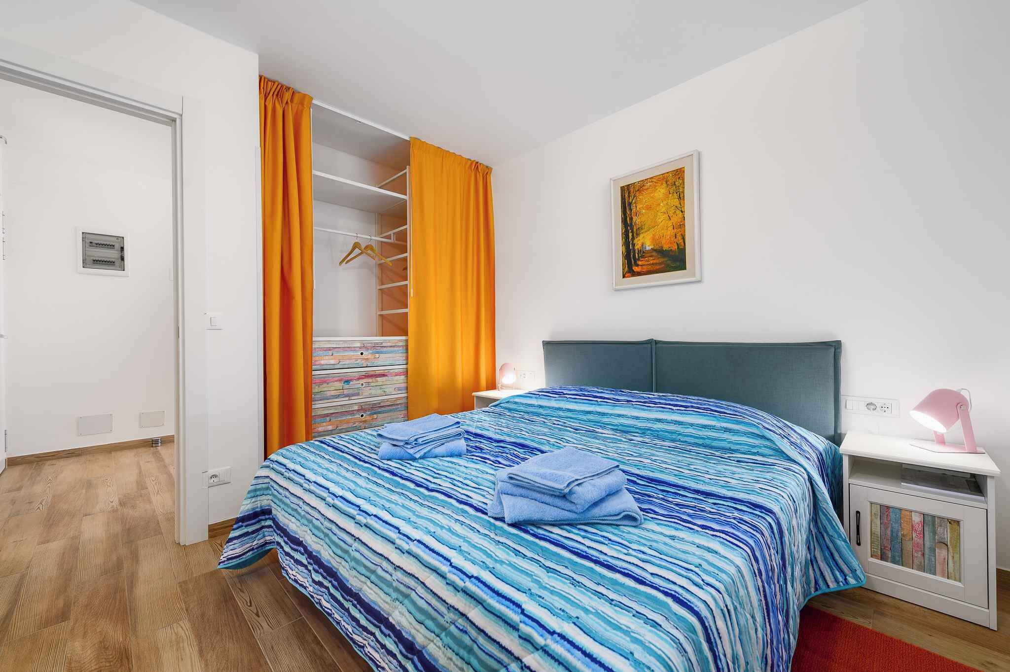Een slaapkamer met een bed, nachtkastje, kledingkast en een schilderij aan de muur.