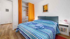 A bedroom with a bed, a nightstand, a wardrobe, and a painting on the wall. - Holiday apartment near the beach and with air conditioning (Umag)