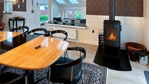 Une cuisine moderne dotée d’un îlot central, d’un coin repas avec une table en bois et d’un poêle à bois.