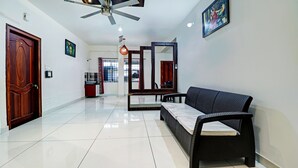 A hotel lobby with a modern design, featuring a large mirror, a sofa, a ceiling fan, and a tiled floor. - Itsy Hotels Colors Stay (Chikkamagaluru)