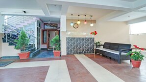 A spacious lobby with a staircase, a reception desk, and a seating area with potted plants. - Itsy Hotels Colors Stay (Chikkamagaluru)