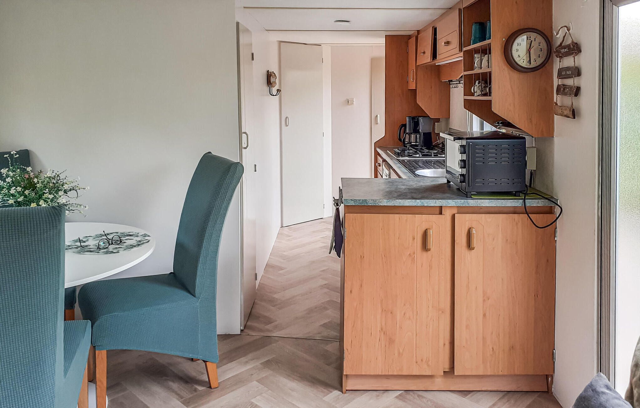 Una cocina compacta con armarios de madera, una pequeña encimera y un reloj en la pared.