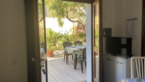 An open door leading to a patio with a table and chairs, a television, and a calendar on the wall.