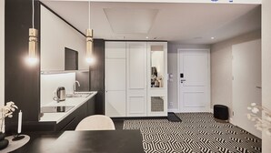 A modern kitchen with a built-in stove, a sink, and a mirror above the countertop. There is a dining area with a table and chairs, and a patterned floor. - Apartamenty Świnoujście - Uzdrowiskowa 40G (Swinoujscie)