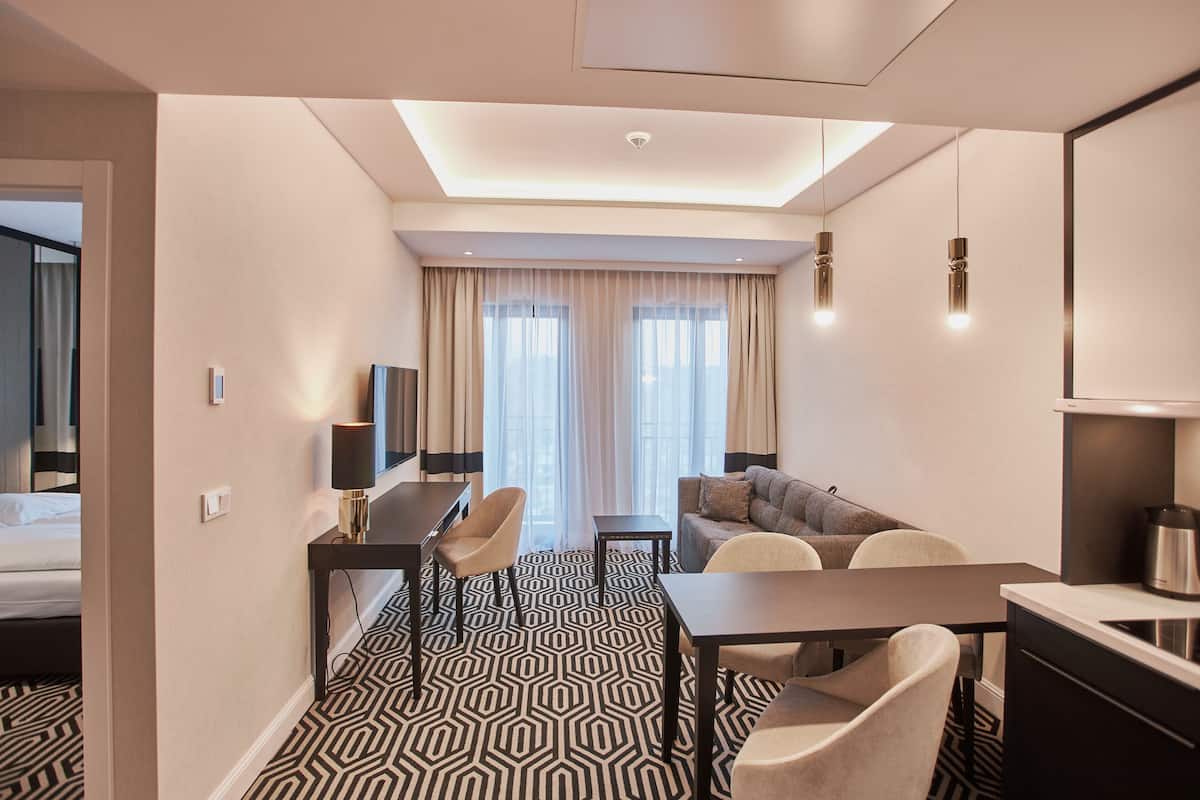 Una habitación de hotel con cama, escritorio con silla, sofá y kitchenette.