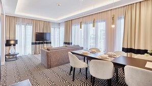 A modern hotel room with a dining area, a sofa, and a TV. - Apartamenty Świnoujście - Uzdrowiskowa 40G (Swinoujscie)