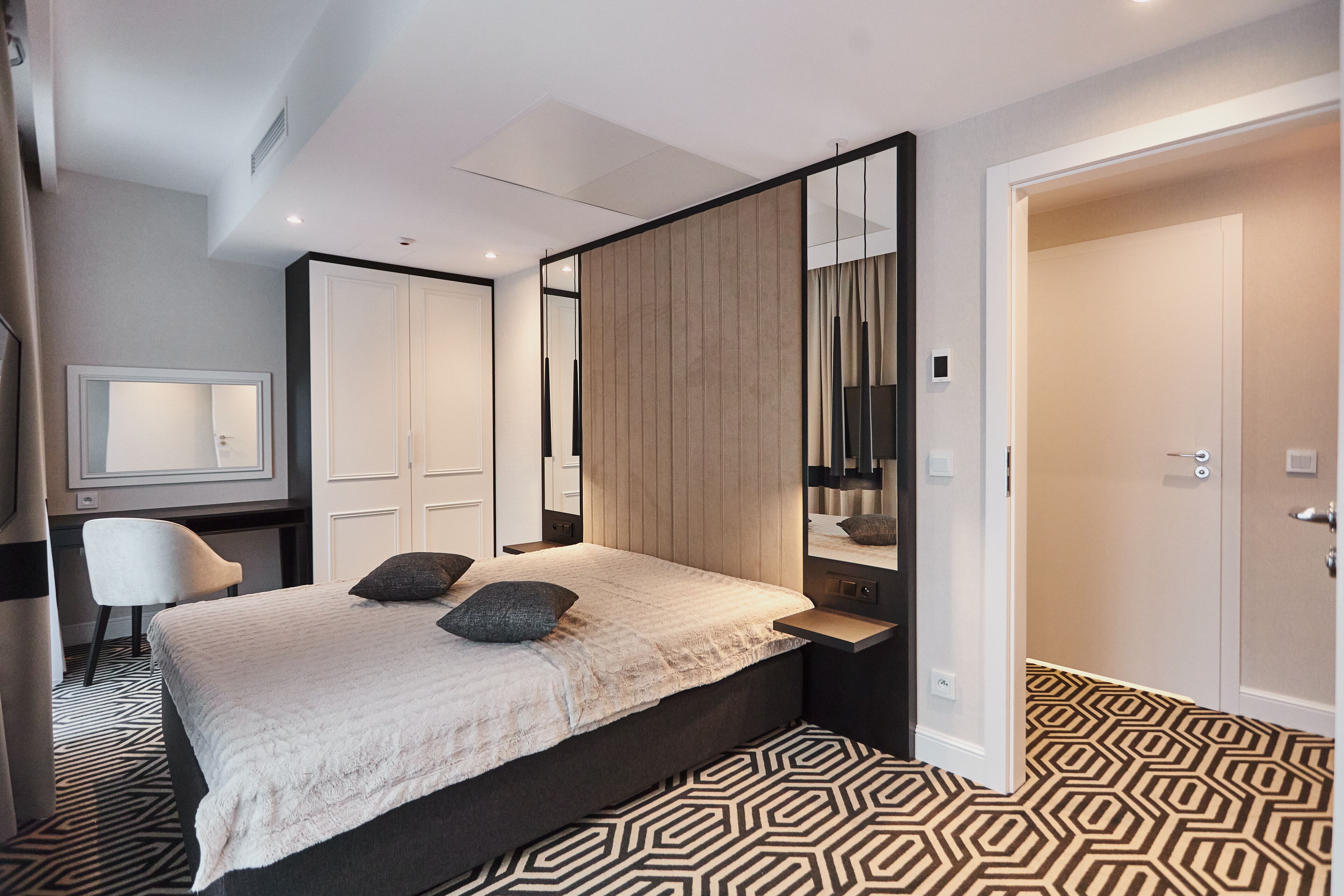 Ein modernes Hotelzimmer mit einem großen Bett, einem Schreibtisch, einem Stuhl und einem Kleiderschrank.