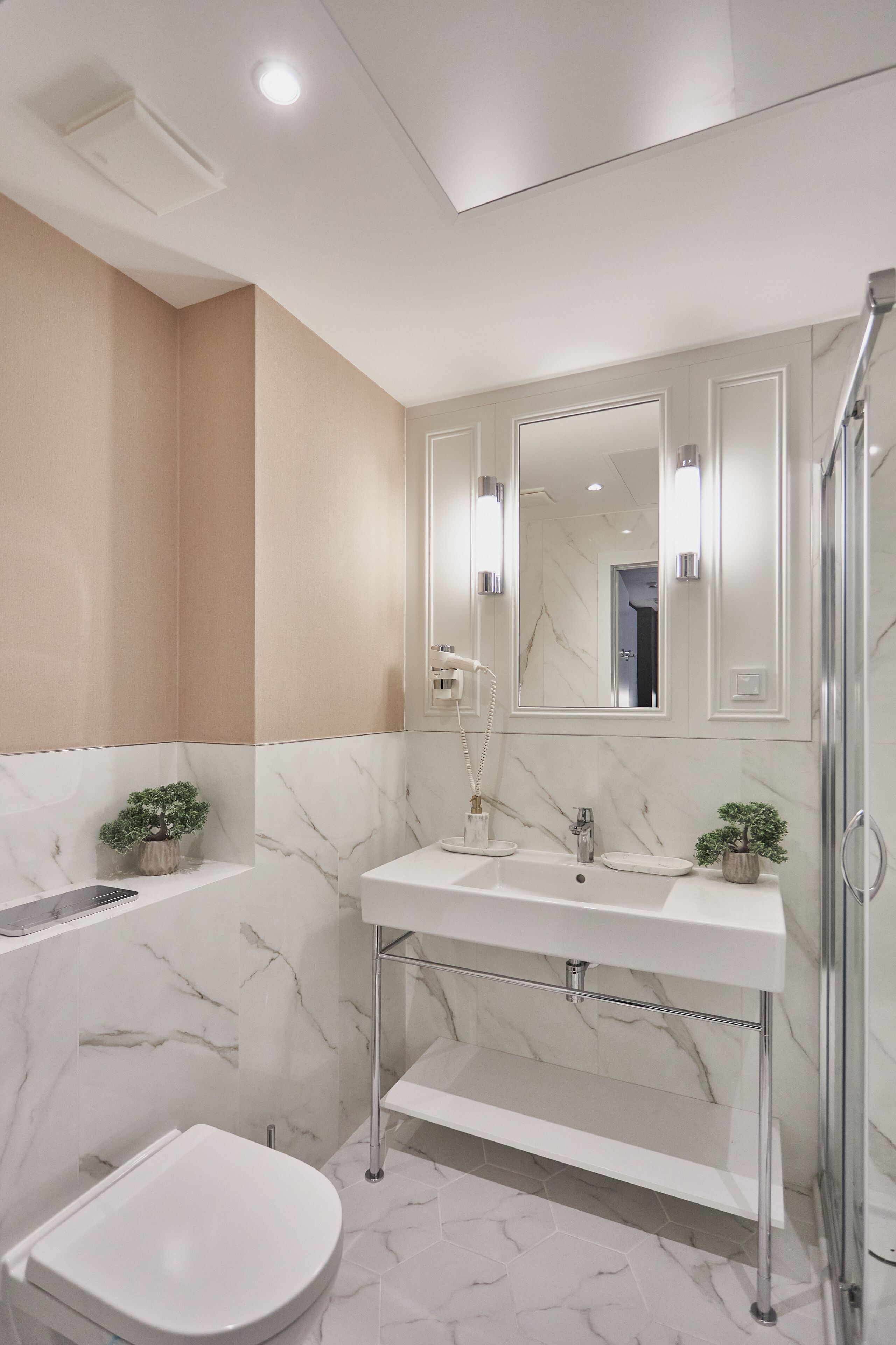 A modern bathroom with a white toilet, a sink with a marble countertop, and a shower area.