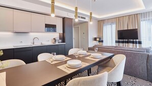 A modern hotel room with a dining area, a sofa, and a TV. - Apartamenty Świnoujście - Uzdrowiskowa 40G (Swinoujscie)