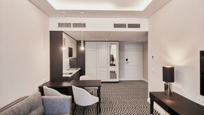 A modern hotel room with a dining area, a sofa, a TV, and a patterned floor. - Apartamenty Świnoujście - Uzdrowiskowa 40G (Swinoujscie)