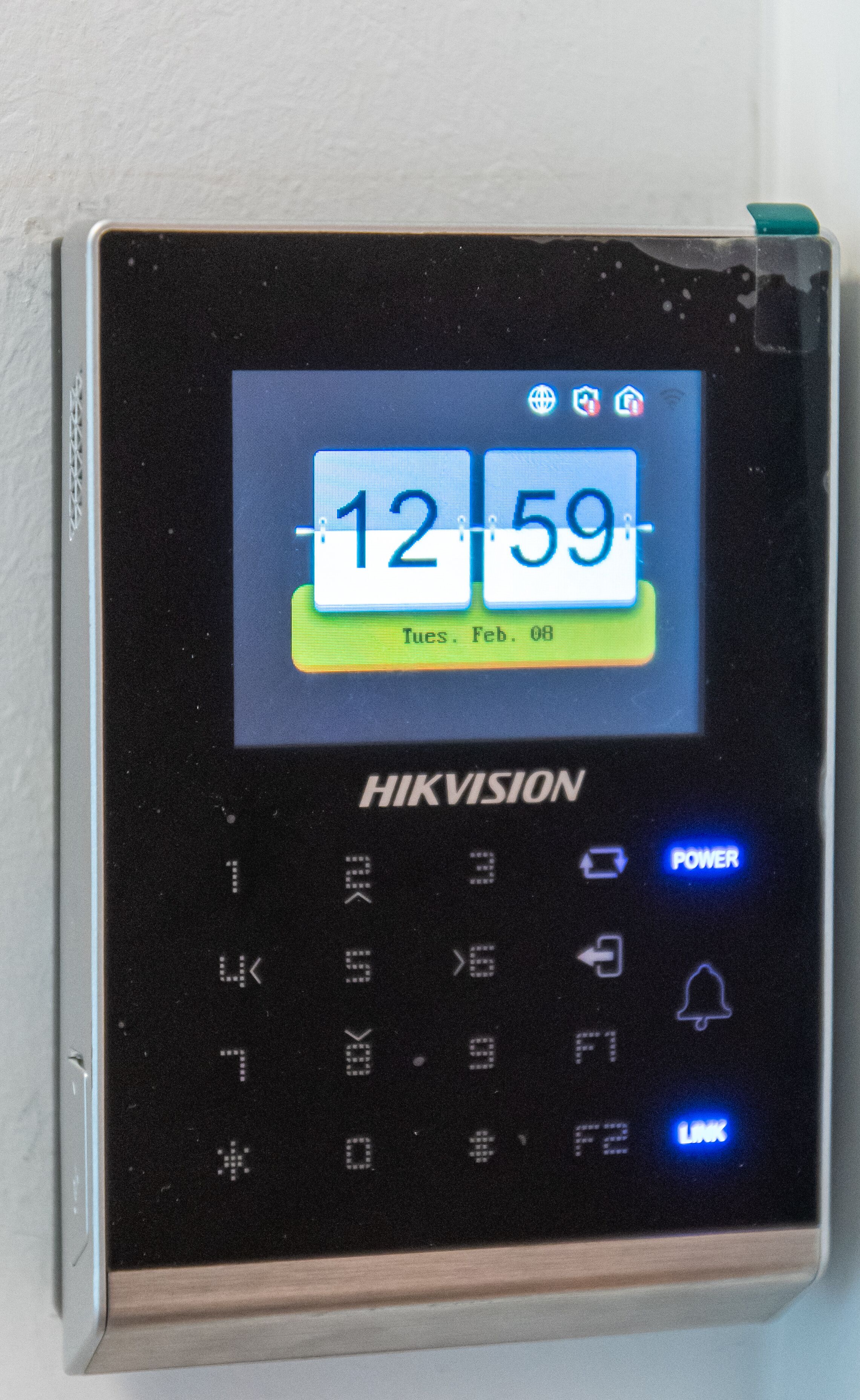 Een HIKVISION digitale klok toont 12:59 uur op een dinsdag, 8 februari.