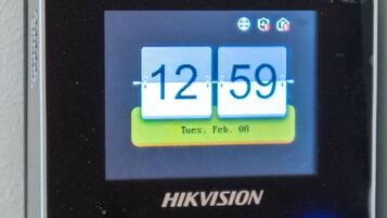 Een HIKVISION digitale klok toont 12:59 uur op een dinsdag, 8 februari.