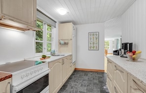 Enjoy meals in this kitchen with a sink, stove, and window overlooking the greenery.