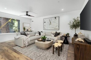 A modern living room with a sofa, coffee table, and a TV stand.