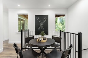 A dining area with a round table, black chairs, and a black and white deer artwork on the wall.
