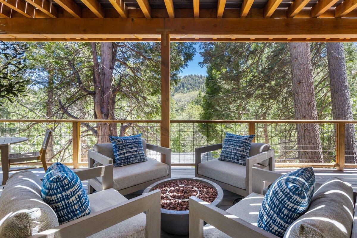 An outdoor seating area with a fire pit, surrounded by wooden furniture and blue patterned cushions.