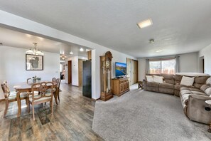 A spacious living area with a dining table, a large sofa, and a television.