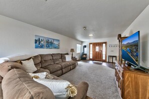 A living room with a large brown sectional sofa, a flat-screen TV on a wooden stand, and a fireplace.