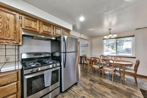 Una cocina moderna con electrodomésticos de acero inoxidable, armarios de madera y un comedor con mesa y sillas de madera.