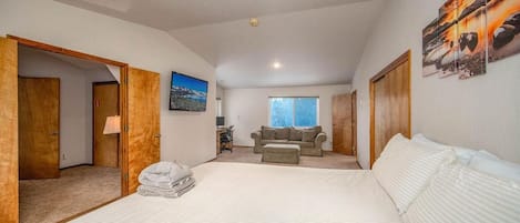 Un dormitorio con una cama grande, un escritorio, un sofá y vistas al exterior.