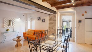 Un salon moderne avec une table à manger en verre, un canapé orange et un mur décoratif en pierre.