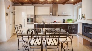 Une cuisine moderne avec des meubles blancs, une table à manger avec des chaises et une cheminée.