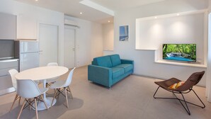 Un salon moderne avec une table à manger blanche, un canapé turquoise et un fauteuil marron.