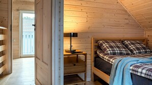 A wooden room with a bed, a desk, and a window.